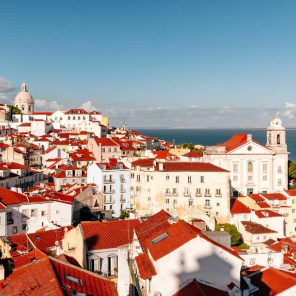 Blick auf die weißen Häuser mit ihren rotleuchtenden Dächern in Lissabons Altstadtviertel Alfama.