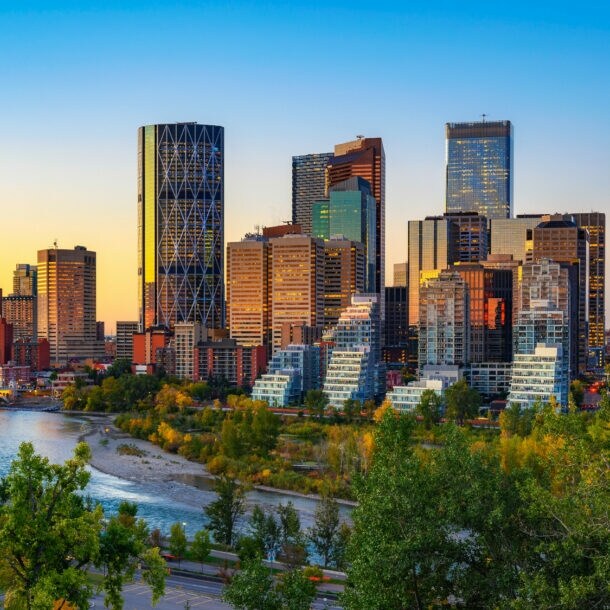 Sonnenuntergang über der Skyline der kanadischen Stadt Calgary, mit dem Bow River im Vordergrund.
