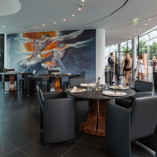 Stehende Personen in einem modernen Restaurant in einem lichtdurchfluteten Gebäude mit Glaskuppel.