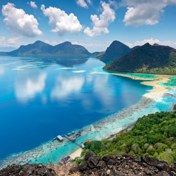 Panorama mehrerer Inseln mit bewaldeten Hügeln und Lagune im türkisblauen Meer.