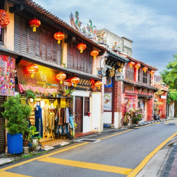 Schmale Straße mit Geschäften und roten Lampions um den Eingang zu einem chinesischen Tempel.