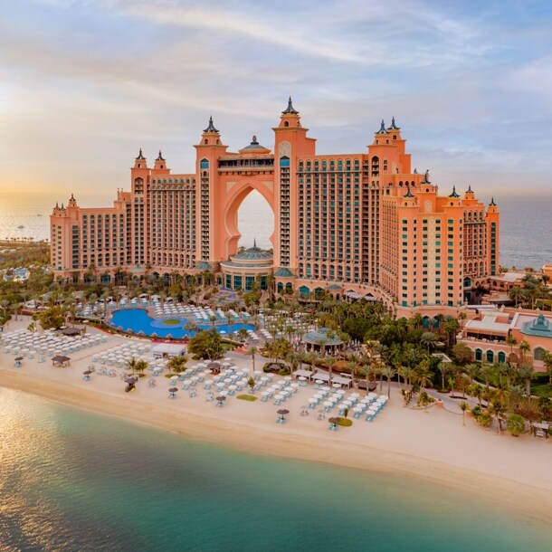Luxuriöser Hotelkomplex mit Türmen auf einer Insel mit Gartenanlage und Pool an weißem Sandstrand.