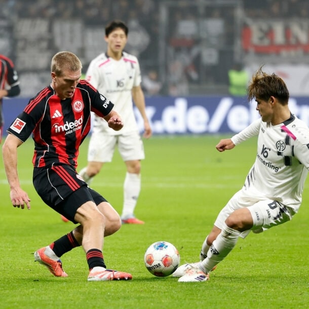 Zwei Fußballspieler gegnerischer Mannschaften im Ballduell auf dem Rasen in einem Fußballstadion.