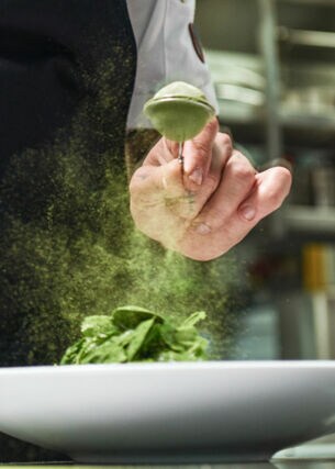Koch würzt Gericht mit Matcha in Restaurantküche