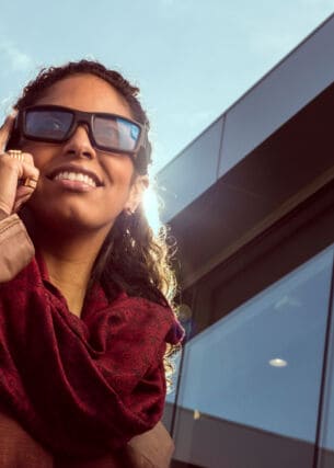 Eine Frau trägt eine Sonnenbrille die sie mit dem Fingern antippt