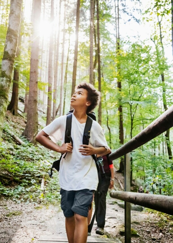 Ein Junge mit Rucksack wandert durch den Wald und beobachtet die Natur
