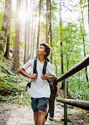 Ein Junge mit Rucksack wandert durch den Wald und beobachtet die Natur