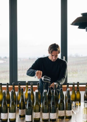 Winzer Jochen Dreissigacker beim Wein einschenken vor einem Tisch mit Weinflaschen