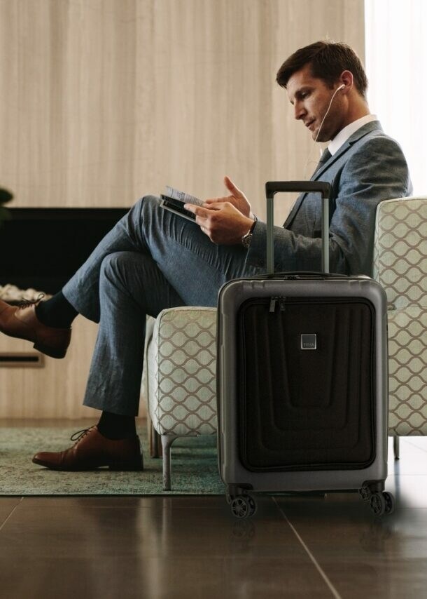 Ein Mann in einem Sessel, neben ihm steht ein Koffer