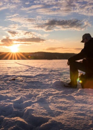 Ein Eisangler sitzt auf einem zugefrorenen See