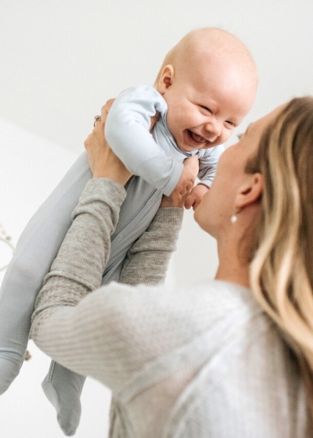 Frau hebt lachendes Baby in die Luft