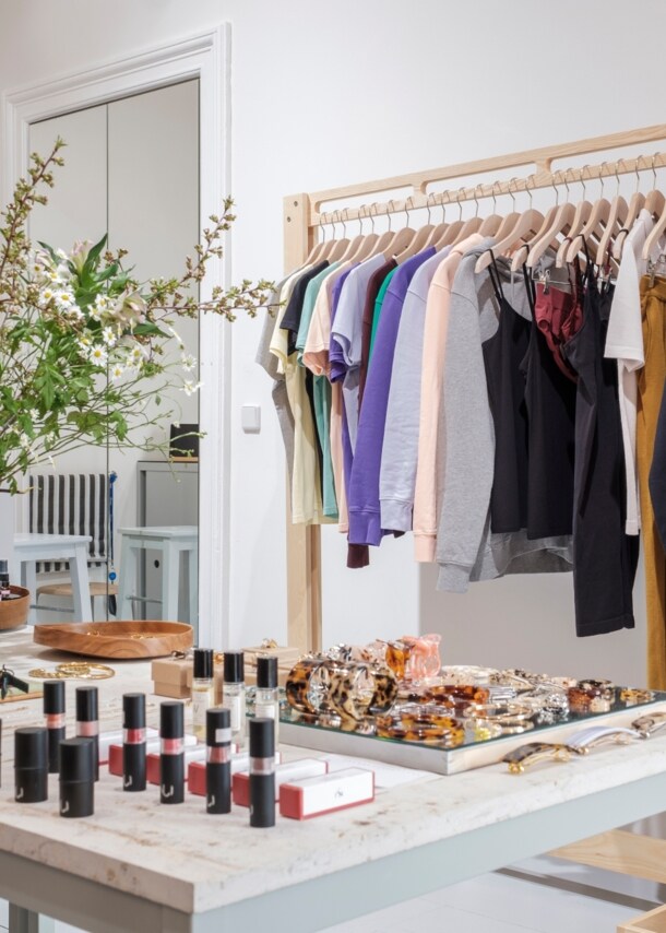 Innenansicht eines Geschäftes mit Kleidung, Make Up und einem Blumenstrauß auf einem Tisch