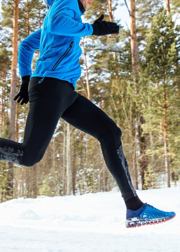 Ein Mann joggt im verschneiten Wald.