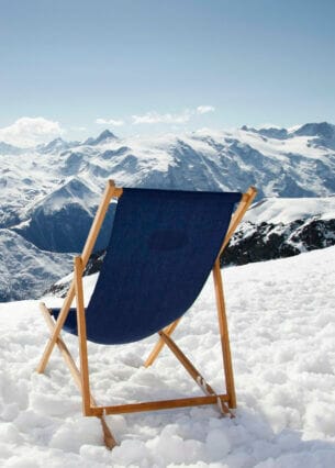 Ein Liegestuhl und Ski mit Stöcken auf einem Berg im Schnee