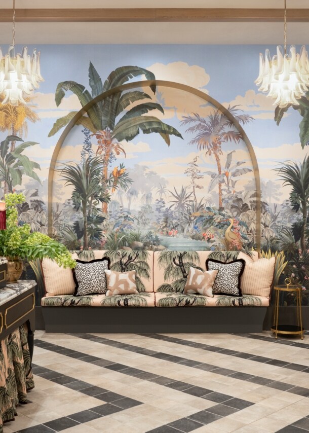 Hotellobby mit Rezeption, Couch, Aufzug und einer Palmentapete