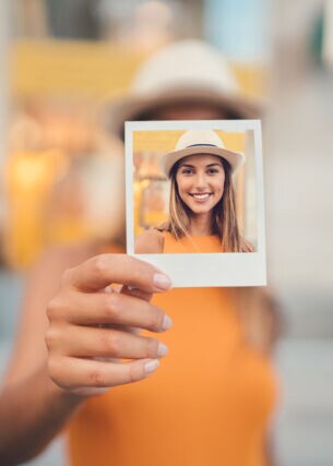Eine junge Frau hält ein Polaroid in der Hand mit einem Selbstportrait