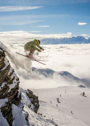Eine Person auf Ski fliegt einen schneebedeckten Hang hinab