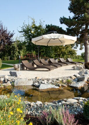 Ein gestalteter Garten mit Liegestühlen an einem bepflanzten Teich