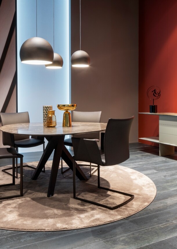 Ein runder Tisch und ein schlichtes Sideboard auf einem Messestand der imm cologne