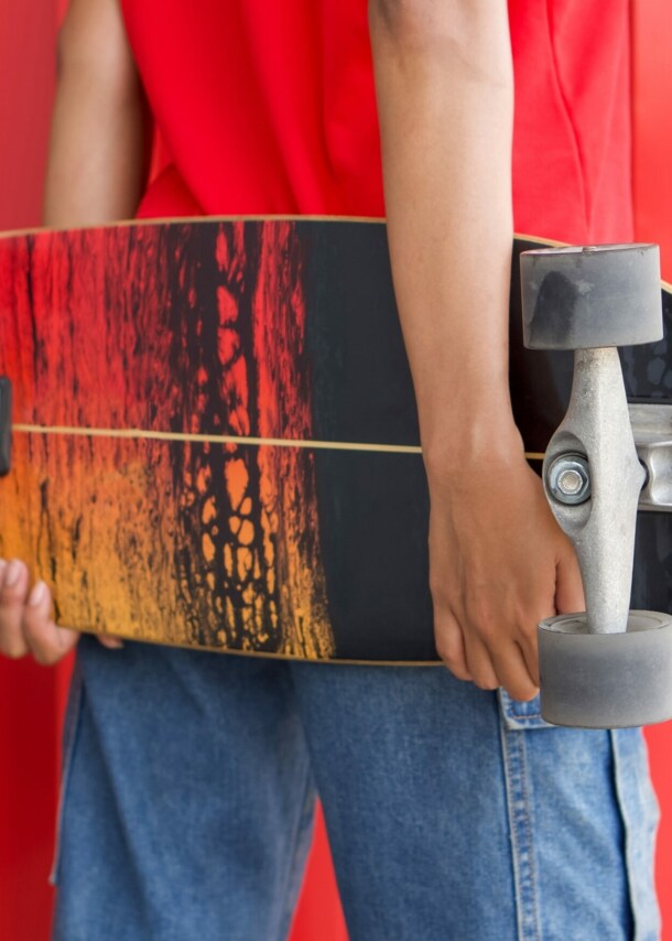 Rückansicht einer Frau, die ein Longboard hinter dem Rücken hält