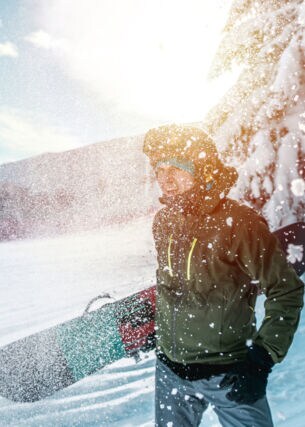 Ein junger Mann mit einem Snowboard unter dem Arm