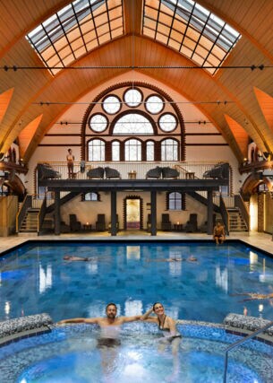 Innenraumansicht einer Schwimmhalle mit Saunalandschaft und Whirlpool im historischen Gebäude mit Kuppeldach