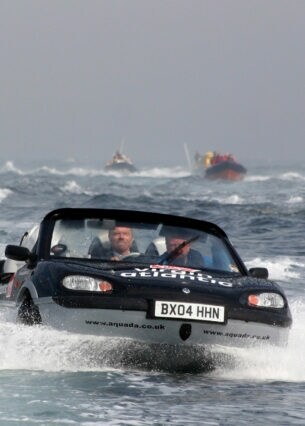 Ein Amphibienfahrzeug fährt auf dem Wasser zwischen mehreren Schiffen