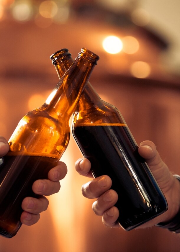 Zwei Hände, die mit Bierflaschen anstoßen