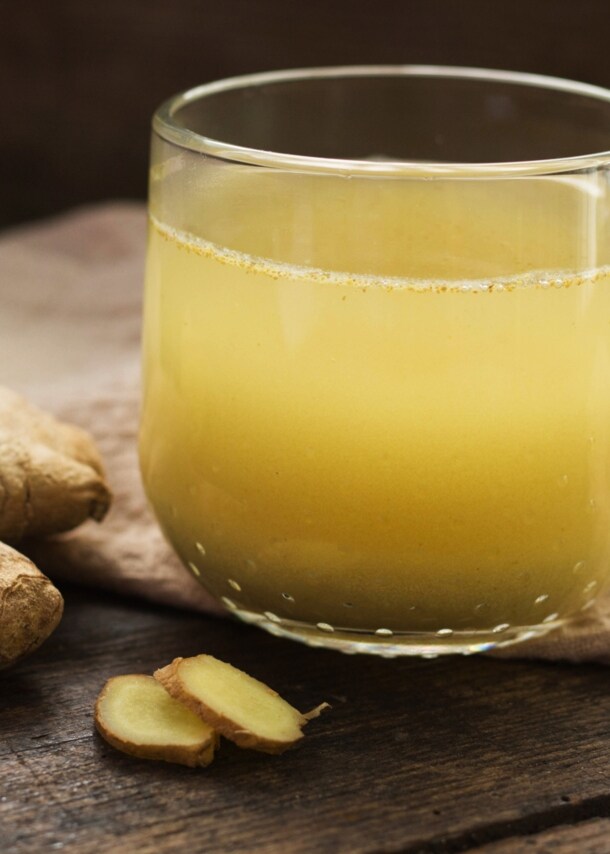 Eine Tasse Ingwer-Tee steht auf einem auf einem Holzbrett