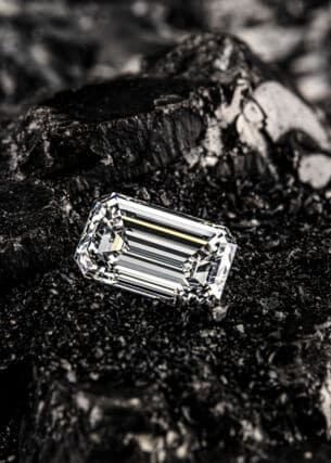 Einzelner Smaragddiamant auf schwarzem Kohlehintergrund.