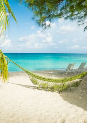 Eine Hängematte hängt am Sandstrand auf Jamaika