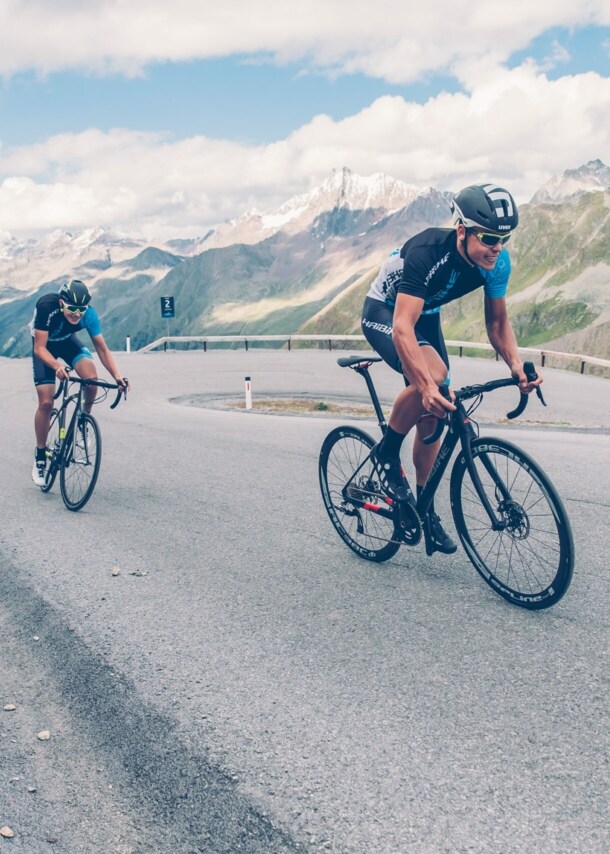 Zwei Rennradfahrer auf einer Bergstraße.