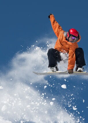 Ein Snowboarder hält sich an dem Board an seinen Füßen bei einem Sprung in der Luft fest