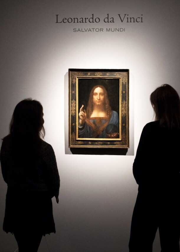 Rückansicht mehrerer Personen als Silhouetten, die Leonardo da Vincis Gemälde Salvator Mundi in einem goldenen Rahmen an einer weißen Wand betrachten