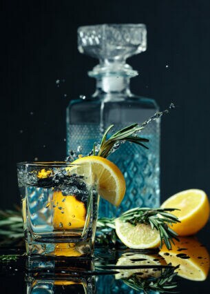 Ein Glas mit Gin Tonic, garniert mit Zitrone und Rosmarinzweigen.