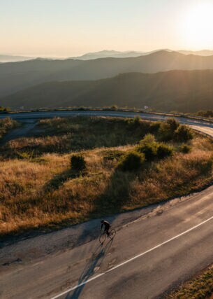 Ein Radfahrer auf einer einsamen Straße im Sonnenuntergang.