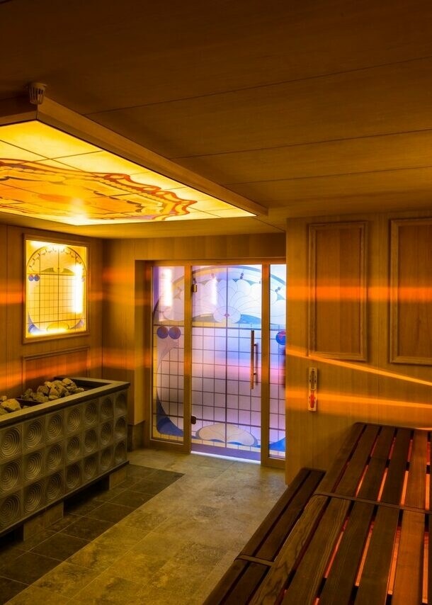 Holzsauna mit gelben, dekorierten Glasplatten, durch die Lichtstrahlen ins Innere dringen
