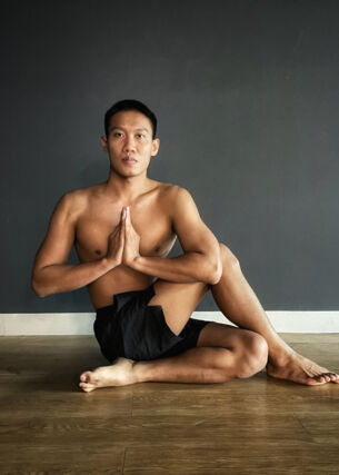 Mann macht Yoga, sitzt im halben Drehsitz