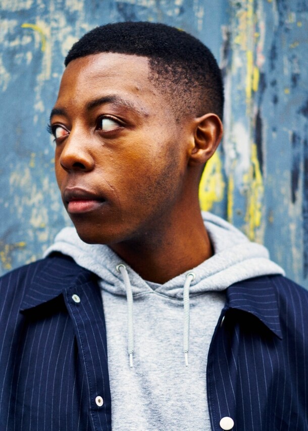 Close-Up eines jungen Mannes in Hoodie und Hemdjacke.