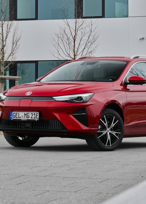 Roter Kombi vor einem großen grauen Haus