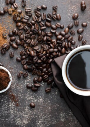 Kaffeebohnen, gemahlener Kaffee und eine Tasse Kaffee von oben fotografiert.