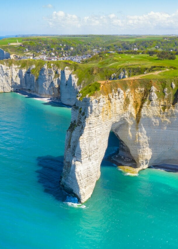Eine imposante Steilküste, die von türkisfarbenem Meer umzingelt wird.