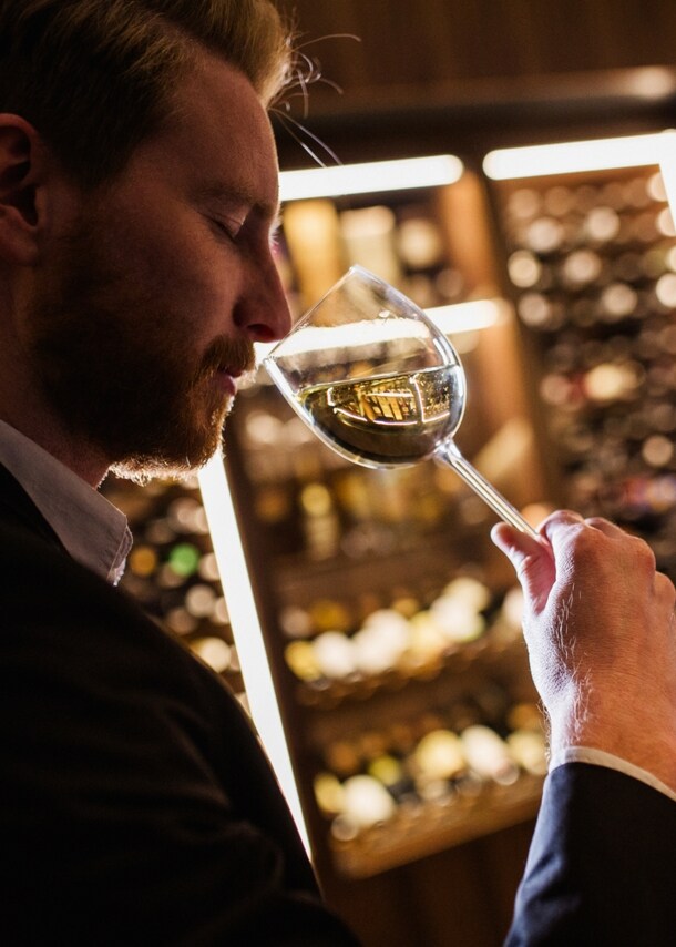 Ein Mann riecht an einem Weinglas.