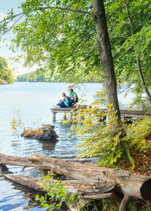Wanderer pausieren auf einem Steg am Schmalen Luzin im Naturpark Feldberger Seenlandschaft