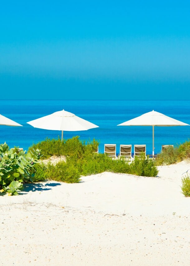 Sandstrand und blaues Meer mit Sonnenliegen und Sonnenschirmen