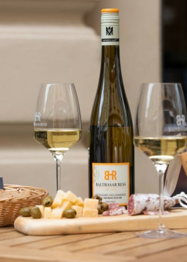 Eine Weinflasche, zwei gefüllte Gläser und Snacks auf einem Holztisch