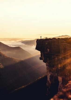 Aussicht auf einen Reisenden, der an einem sonnigen Tag auf einem Felsvorsprung steht.