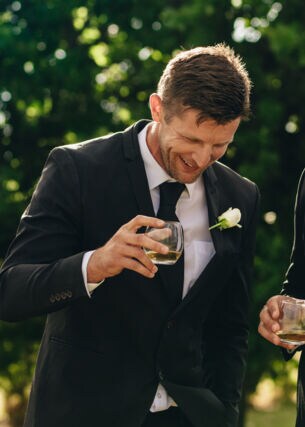 Bräutigam und Trauzeuge trinken und lächeln während der Hochzeitsfeier