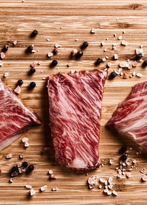 Drei Kobe-Rind-Stücke auf Holz mit Pfeffer und Salz