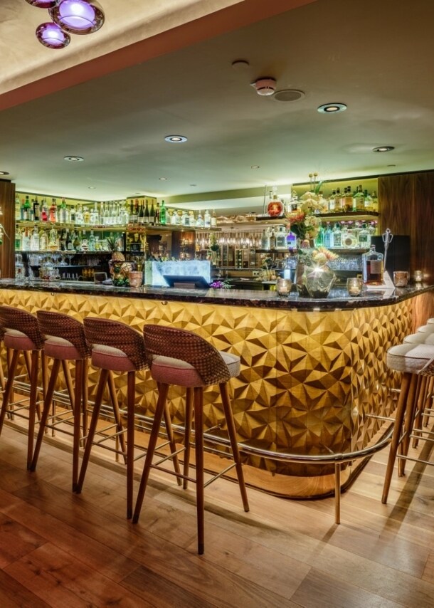 Innenraum einer modern eingerichteten Bar mit gepolsterten Barhockern vor einem Tresen